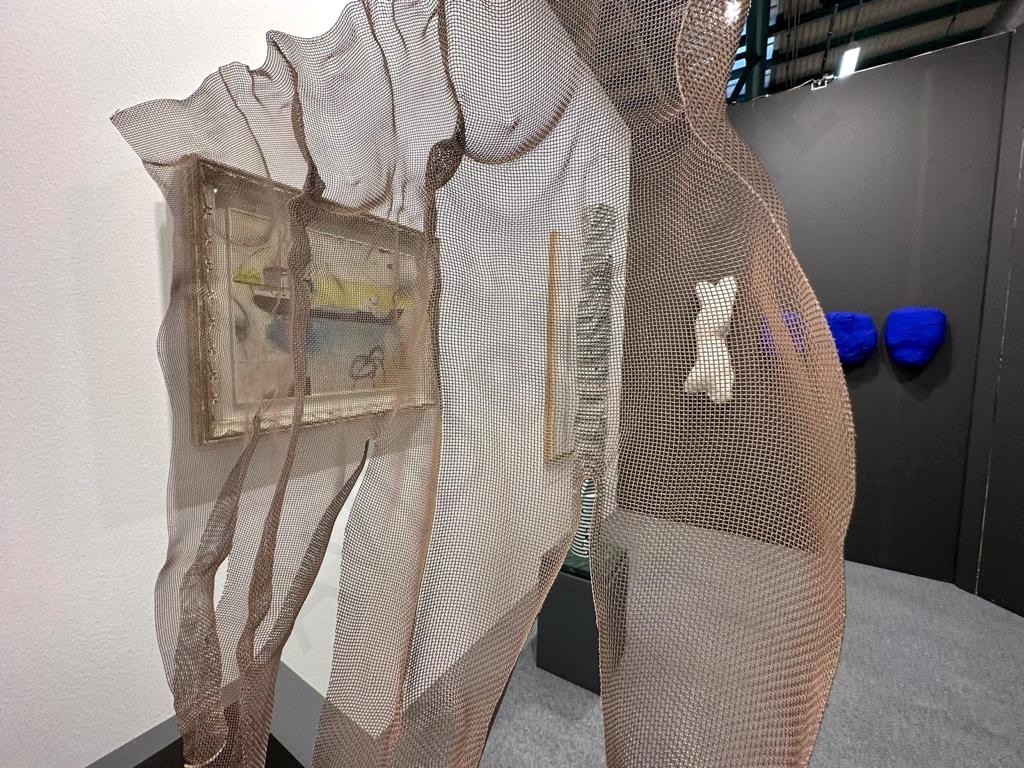 View through a semi-transpartent artwork to suspended sculptures at Artfair BAF 2023