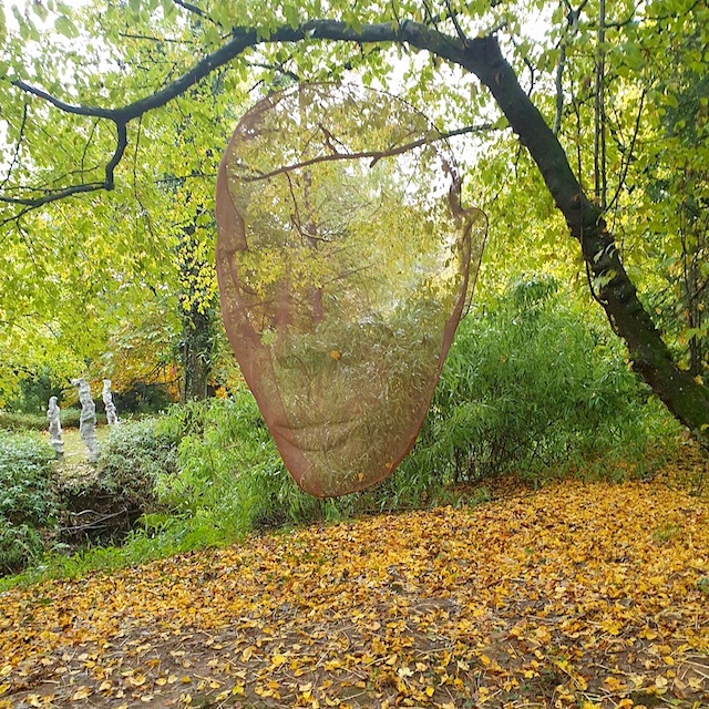 A large face sculpture in an autumnal garden by artist David Begbie