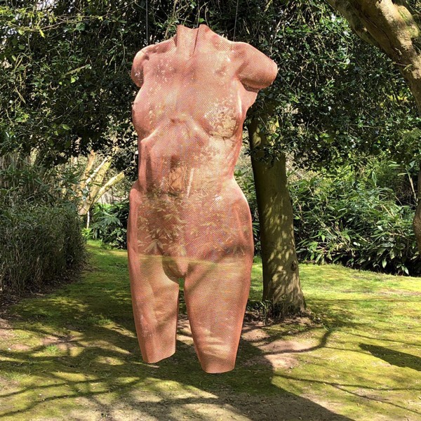 A copper torso is suspended in a sculpture park